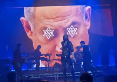 באמצע ההופעה: להקת הרוק הקרינה תמונות של נתניהו וקלינטון עם צלב קרס ומגן דוד בעיניים